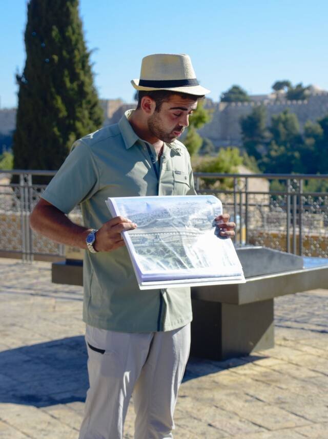 Yona Shemesh showing a historic photograph of Jerusalem, the Old City walls behind