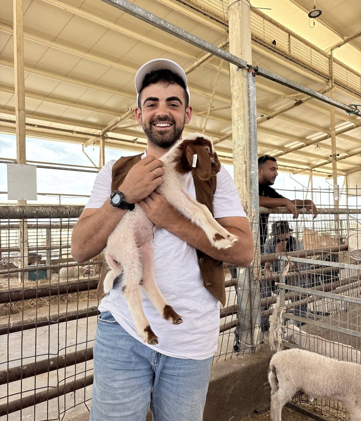 Yona Shemesh holding a kid goat at a farm in Gush Etzion