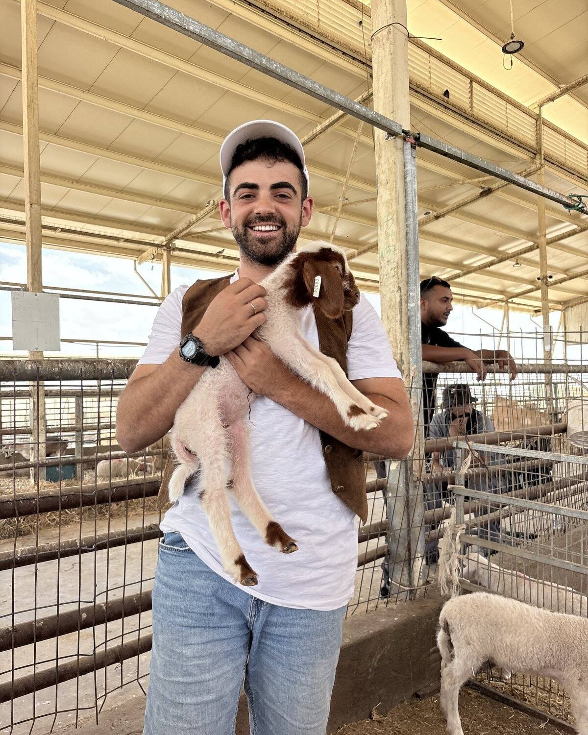 Yona Shemesh holding a kid goat at a farm in Gush Etzion