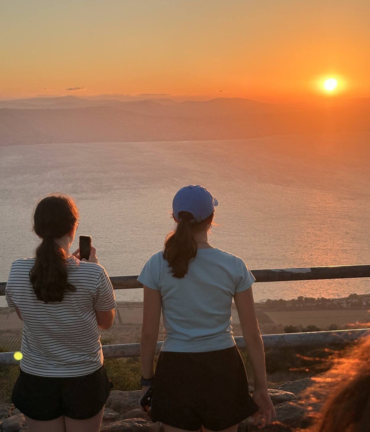 Two travellers watching the sun set over the Sea of Galilee