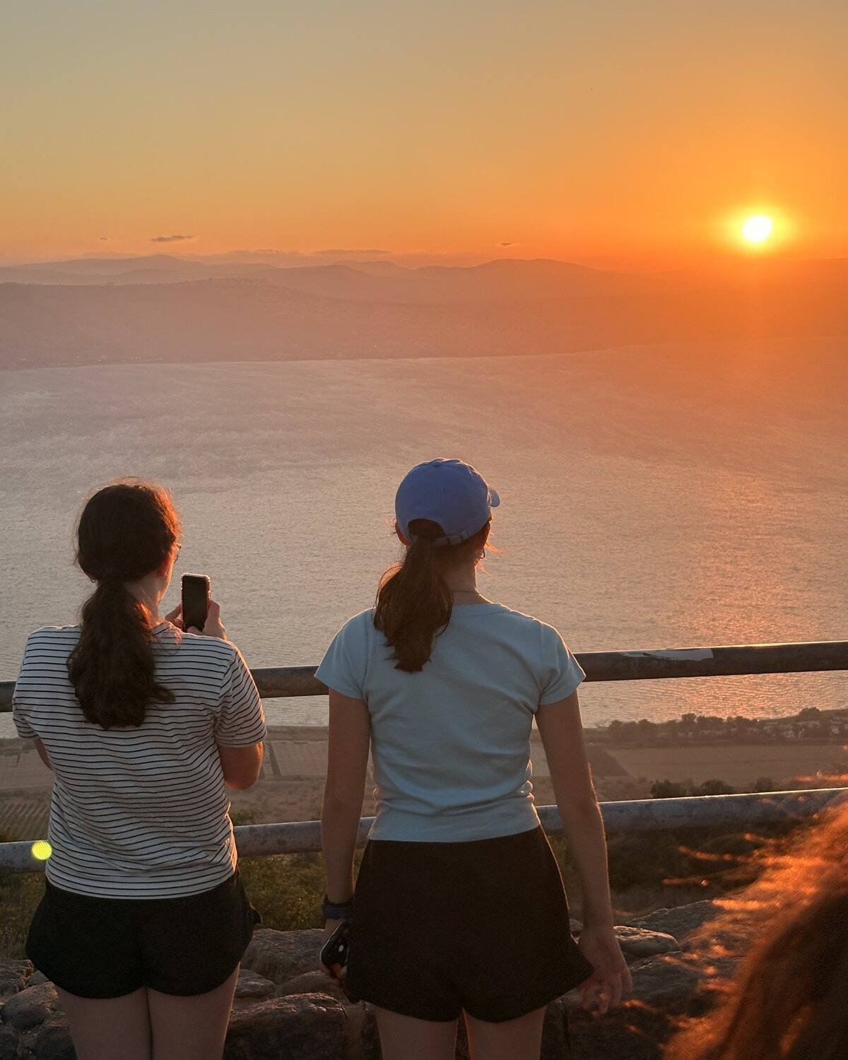 Two travellers watching the sun set over the Sea of Galilee