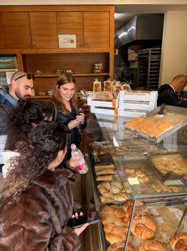 A tour group at a Jerusalem bakery counter, choosing pastries and challah