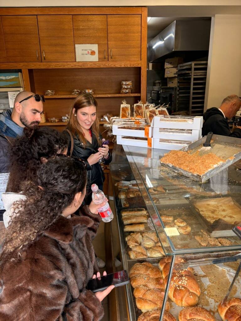 A tour group at a Jerusalem bakery counter, choosing pastries and challah